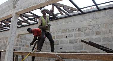Two men on the scaffolding in the shell of a hospital in Liberia