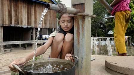 Girl fetching water at water well. 