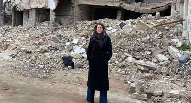 Asja Hanano steht vor zerstörten Häusern in Homs, Syrien.