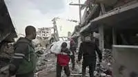 Menschen stehen in Gaza in Trümmern von Häusern