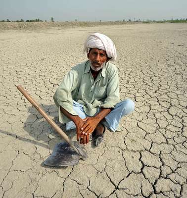 A man sitting on dry ground in Pakistan. The people here have to deal with droughts and floods on a regular basis.