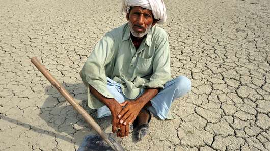 A man sitting on dry ground in Pakistan. The people here have to deal with droughts and floods on a regular basis.