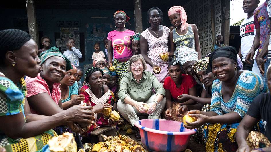 Welthungerhilfe President Marlehn Thieme opening cocoa fruits with a group of women in Sierra Leone.