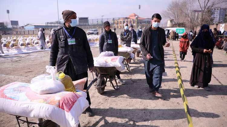 Lebensmittelverteilung in Kabul, Afghanistan: Männer schieben Schubkarren beladen mit Säcken voller Nahrungsmitteln.