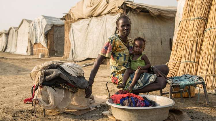 A woman washing clothes with her child at the refugee centre in Bentiu, Southern Sudan.