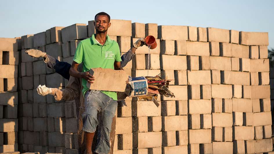 tand one behind the other and stretch out their arms, in each hand they hold a raw material for the production of bricks from waste materials.