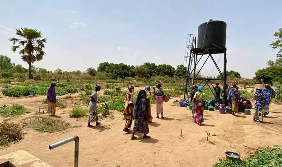 Several people are walking towards a water tower