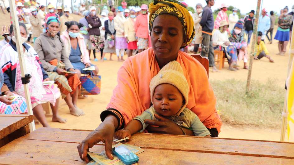 Eine Frau und ihr Baby beim Cash Transfer in Madagaskar.