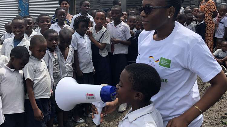 Ein Kind spricht bei einer Schulung über Ebola in ein Megafon.