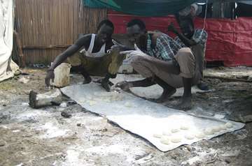 Refugees are preparing bread dough.