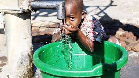 A boy drinks water from the faucet A boy drinks water from the faucet