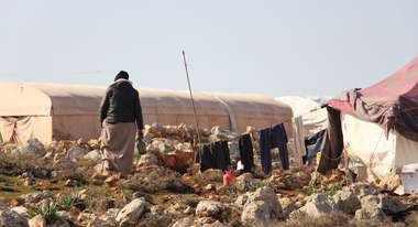 A woman walks to a tent in an informal settlement in Northern Syria.