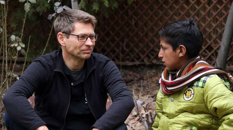 Mathias Mogge im Gespräch mit einem afghanischen Jungen. Sie schauen sich an, Mathias Mogge lächelt. 