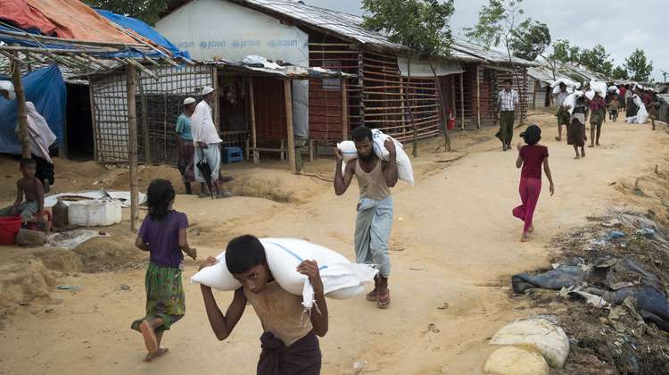 Rohingya refugees are carrying sacks from an aid distribution in camp Hakimpara in Bangladesh, August 2018.