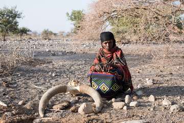Eine Nomadin der Afar sitzt neben einem Kuhskelett. Die Dürre hat alles Wasser vertrocknen lassen.
