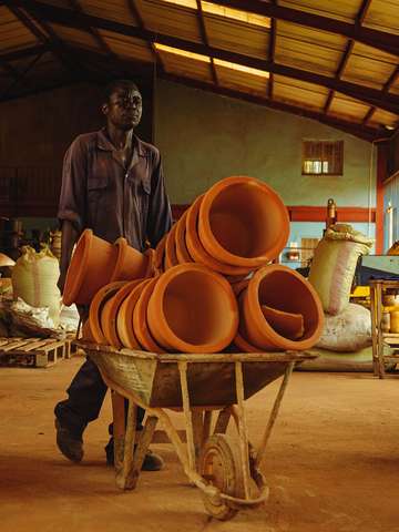 Finished fired clay filters are transported in a wheelbarrow.