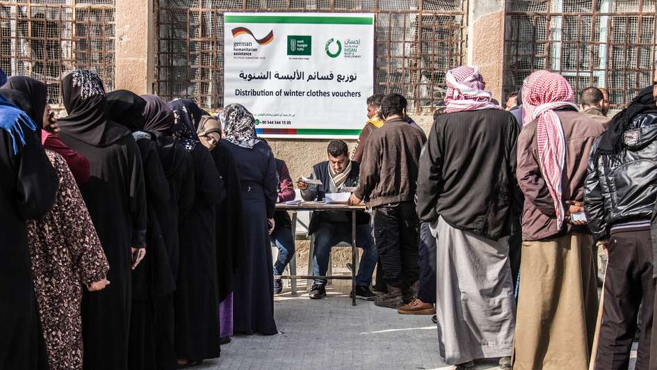 Refugees queuing at distribution of clothing vouchers in Idlib (Syria)
