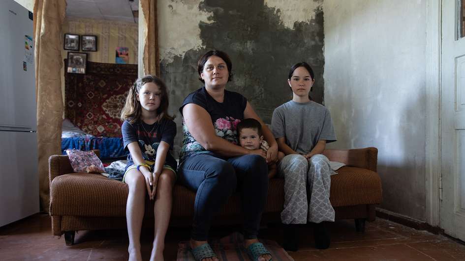 Eine Mutter und ihre drei Kinder sitzen für ein Portraitfoto auf einem Bett.
