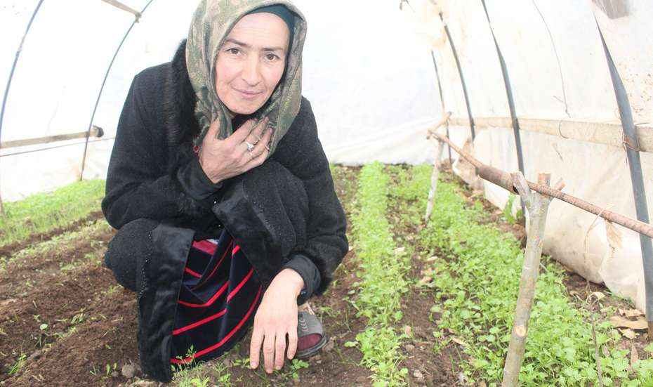 Eine Frau hockt auf dem Boden und kontrolliert den Wachstum der Pflanzen, Tadschikistan 2021.
