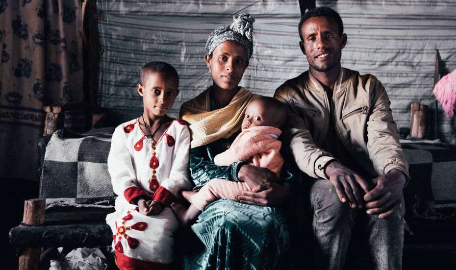 Eine Frau, ein Mann und zwei Kinder sitzen nebeneinander und lächeln in die Kamera.