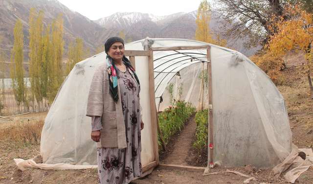Eine Frau steht vor einem Gewächshaus in Tadschikistan, 2021.