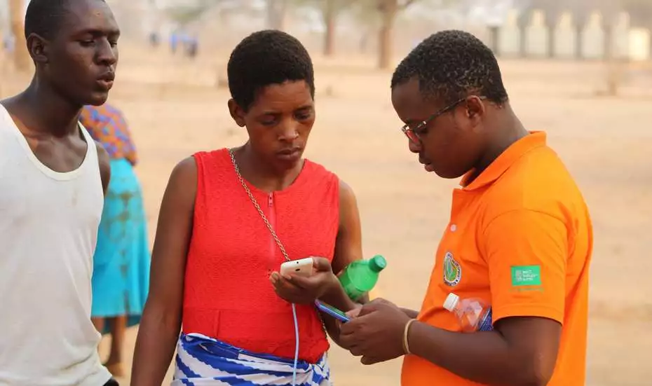 2021-simbabwe-agrishare-putting-customers-in-focus.jpg Zwei Männer und eine Frau mit einem Smartphone in der Hand, Simbabwe 2021.