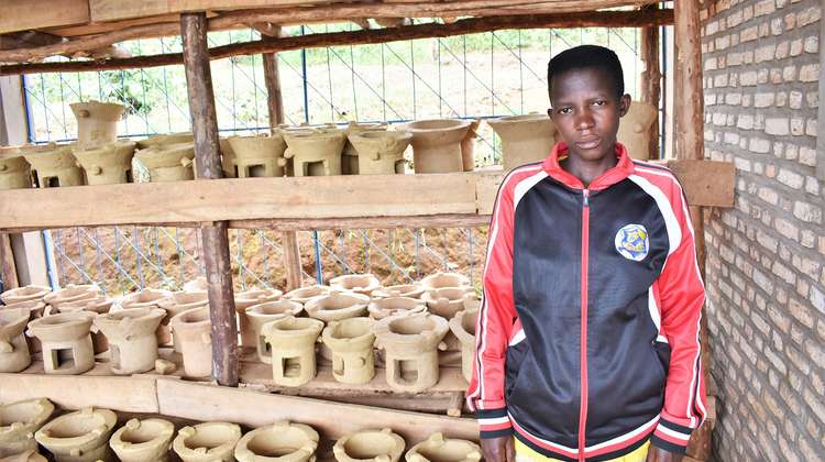 Eine junge Frau zeigt die neuen, effizienten Öfen, die sie baut, Burundi 2021.