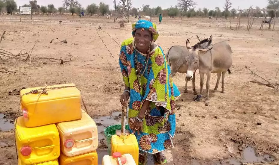 Hawa Sidibé with water cans.