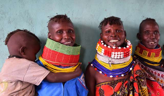 Kenyan women wearing traditional clothing smile towards the camera