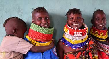 Kenyan women wearing traditional clothing smile towards the camera