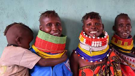 Kenyan women wearing traditional clothing smile towards the camera