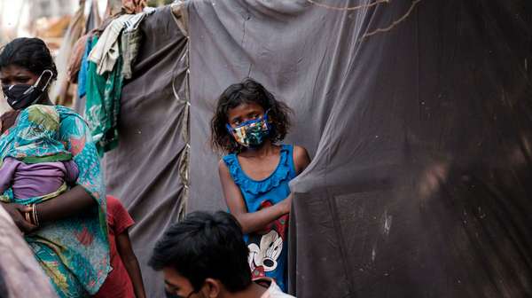 Ein Mädchen mit Mund-Nase-Schutz steht vor einem Zelt