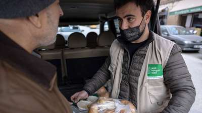 Ein Mitarbeiter der Welthungerhilfe überreicht einem Familienvater ein Paket mit frischen Lebensmitteln