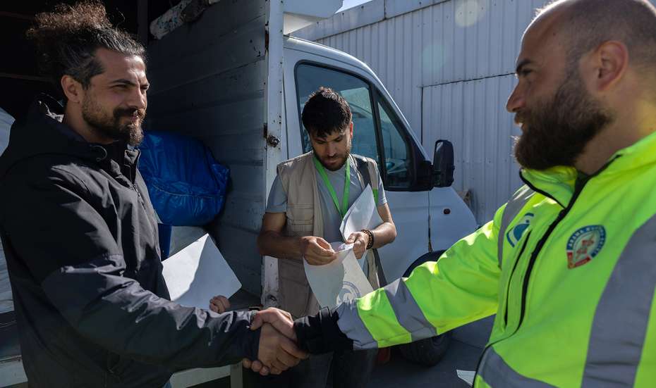 Two men shake hands while loading relief supplies in Türkiye