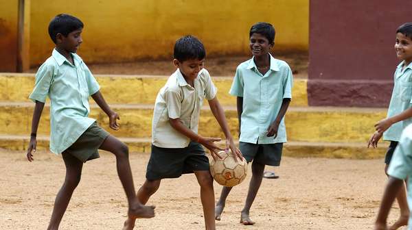 Kinder spielen Fussball im Sand