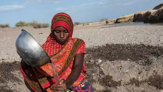 2015-aethiopien-duerre-spendenaufruf-frau-wasser-brockmann-ETH2015BRO005.jpg Vor einer trockenen Landschaft in Äthiopien sitzt eine Nomadin, die Wasser in einen Kanister füllt.