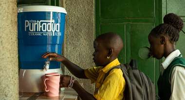 Children take filtered drinking water from a purifier.