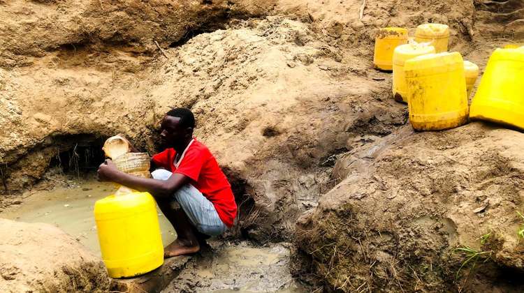 Ein Mann holt Wasser an einer Wasserstelle.
