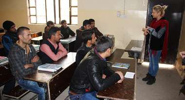 Damaged classroom with young men listening to the teacher