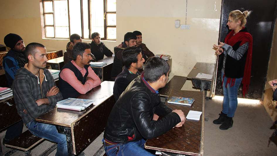 Damaged classroom with young men listening to the teacher