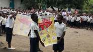 Schulkinder in der Nähe von Goma (D. R. Kongo) halten Informations-Plakate über die Gefahren, Ansteckungswege und Symptome von Ebola sowie über Präventionsmaßnahmen.