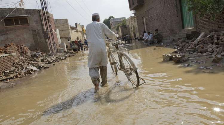 Debris, man with bicycle, floodings in Pakistan.