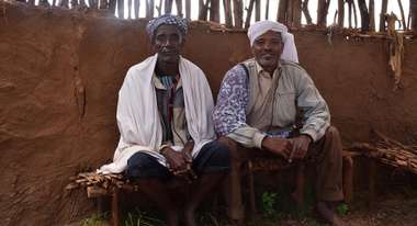 Two Ethopians sitting on chairs.
