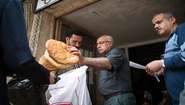 Men puts bread in a plastic bag of a refugee