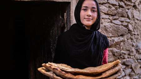 A smiling woman holding flat bread 