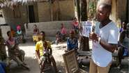 Community members in Bonthe District, Sierra Leone, receive information on behaviour that will help slow down transmission of the virus.
