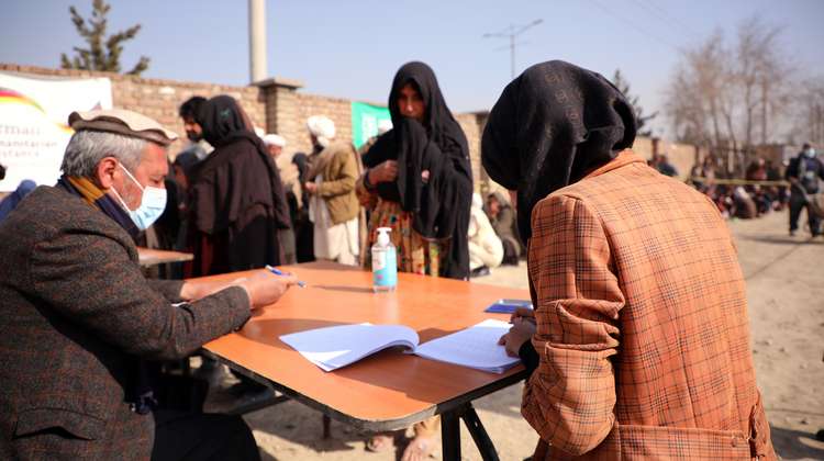 Hilfsgüterverteilung in Kabul: Ein Mann und eine Frau sitzen an einem Tisch und füllen Papiere aus. 