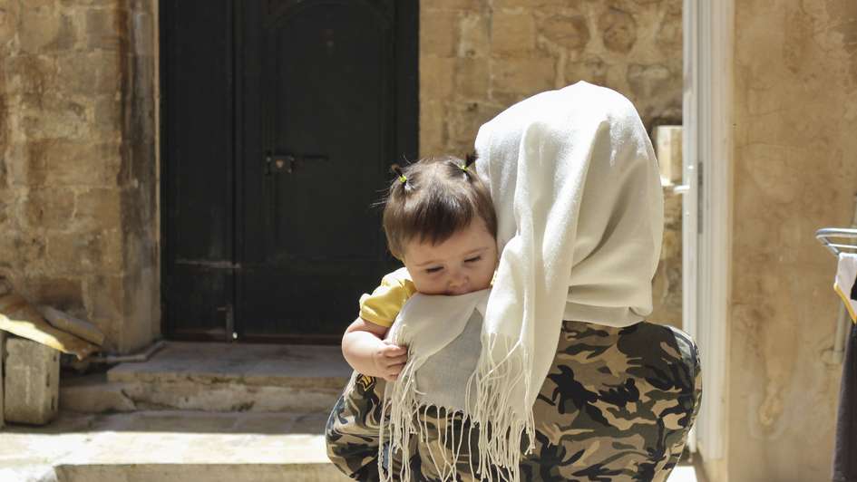 17-year old Melda Almorei holding her child in her parent’s house in Southeastern Türkiye.