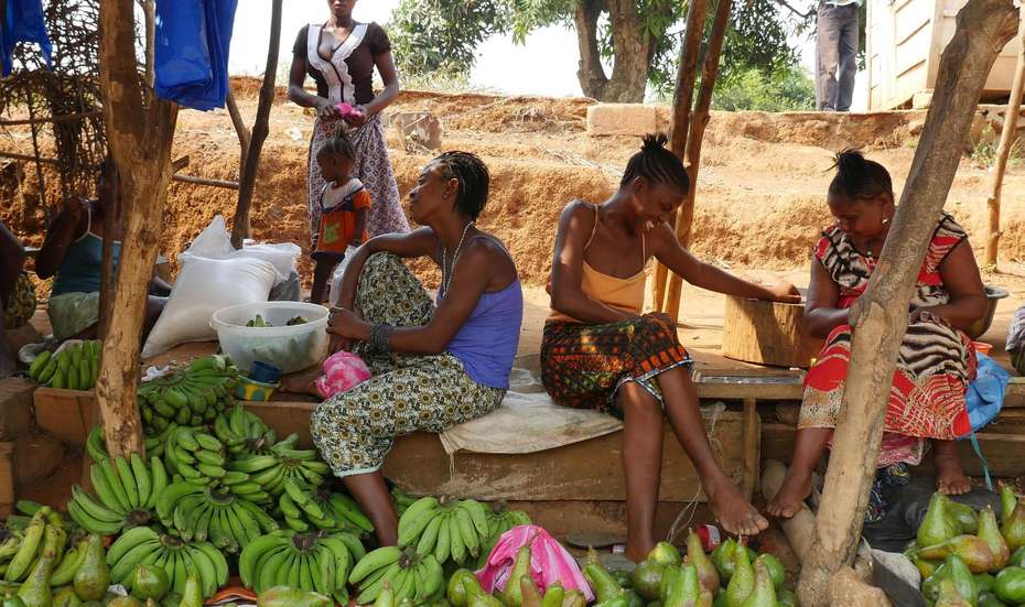 Women are sitting at a food stand.