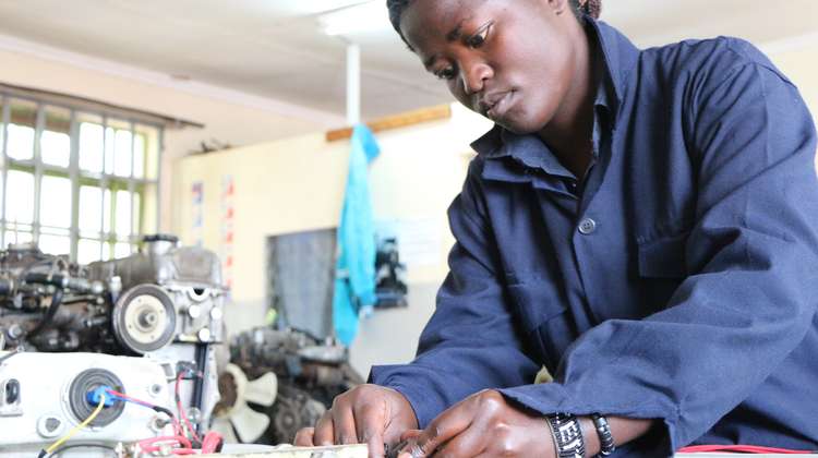 Eine junge Frau in einem blauen Anzug arbeitet als Mechanikerin.